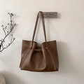 Detail of dark brown leather tote bag hanging on wall with drawstring folding design - Brown