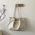 Detail of a minimalist cream white tote bag with knotted strap and leather texture - White