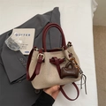 Detail der beigen geflochtenen Eimertasche mit burgunderroten Lederriemen und Anhänger - Mit Anhänger / Rot
