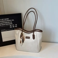Detailansicht der beigen Totebag aus Leder mit braunem Rand und buntem Perlenanhänger - Cremeweiß