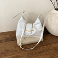 Detailed close-up of white wax leather hobo bag with gold crescent buckle on books - White
