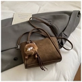 Detailansicht der braunen Wildleder-Eimertasche mit Plüschmonster-Anhänger - Kaffee mit Anhänger