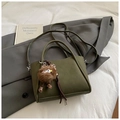 Detail der dunkelgrünen Vintage Beuteltasche mit süßem Plüschmonster auf grauem Blazer - Grün mit Anhänger