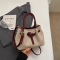 Chic beige canvas and burgundy leather bucket bag shown in a stylish lifestyle setting - No Pendant / Red