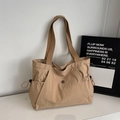 Detail shot of khaki tote bag featuring side drawstring pockets and metallic logo plaque - Khaki