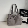 Detail of minimalist dark grey nylon tote bag with drawstring pockets and metal logo - Gray