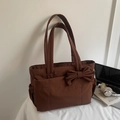 Dettaglio della borsa tote in tela marrone con decorazione a fiocco e tasche laterali - caffè