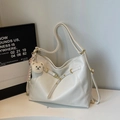 Detail view of cream-white tote bag with golden metal ring and plush bear charm accessory - Off-white