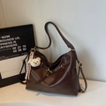 Detail view of large dark brown tote bag with plush bear charm and golden hardware accents - Coffee