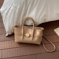 Detail view of beige lychee texture leather handbag with golden round twist lock and handles - Khaki