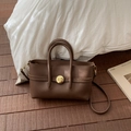Close-up of brown litchi pattern leather bag featuring elegant golden twist lock hardware - Brown