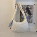 Detalle de bolso medialuna acolchado crema con costuras onduladas y lazo azul suave - Blanco (con Colgante)