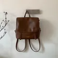 Dettaglio di uno zaino vintage in pelle marrone con cinghie e placchetta in metallo dorato - Marrone