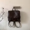 Dettaglio dello zaino vintage in finta pelle marrone scuro con logo e cinturini decorativi - Marrone