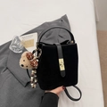Detail of black suede bucket bag with golden rectangular turn-lock and cute bear charm - With Charm / Black