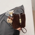 Close-up of dark brown suede bucket bag with leather handle and gold twist lock clasp - With Charm / Coffee