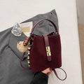 Detail of burgundy bucket bag with golden twist lock and beige plush bear charm - With Charm / Burgundy