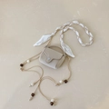 Détail du mini sac beige avec bandoulière ornée d'un foulard en soie et de perles blanches - Blanc Cassé