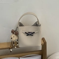 Detailed macro of a cream bucket bag with lychee grain leather and silver bow lock - With Charm / White
