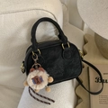 Detail shot of black frosted texture bowling bag with plush bear charm on white sofa - Black with Pendant