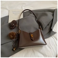 Detailed close-up of dark brown tote bag on grey blazer with gold clasp and fur ball charm - Coffee With Pendant