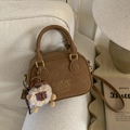 Close-up of retro brown bowling bag featuring embossed logo and a cute alpaca plush charm - Brown with Pendant