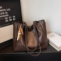 Dettaglio di una grande borsa tote marrone con texture e ciondolo di perline colorate - Marrone