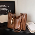 Dettaglio della borsa tote color caramello con scritta 'FASHION & YM' e ciondolo di perle - Marrone