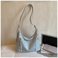 Hellgraue Hobo-Schultertasche aus Kunstleder mit Reißverschluss-Quasten auf einem Tisch - Blau