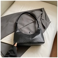 Classic black woven leather shoulder bag in crescent shape placed on a gray blazer - Black (Without Charm)