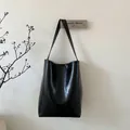 Detailansicht einer schwarzen Lederbeuteltasche mit Öl-Wachs-Finish und geprägtem Markenlogo - Schwarz