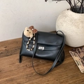 Detail der schwarzen Ledertasche mit weißen Nähten und einem silbernen Drehverschluss - Mit Anhänger / Schwarz