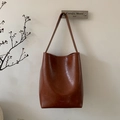 Detailaufnahme einer braunen Vintage-Eimertasche aus glänzendem Öl-Wachs-Leder - Rotbraun