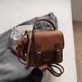 Detail of vintage brown leather handbag with metal buckles and a cute bear keychain accessory - With Pendant / Brown