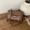 Detailed view of a brown vintage matte handbag with silver swivel lock on a wooden desk - No Pendant / Brown