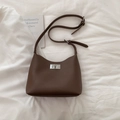 Detail of dark brown lychee leather texture and silver metal rotating lock on shoulder bag - Brown