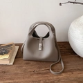Detail einer grauen Beuteltasche aus Leder mit Narbenstruktur und silbernem Drehverschluss - Grau