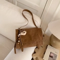 Close-up of vintage brown leather handbag with a plush bear charm on a cozy sofa - With Charm / Brown