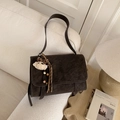 Detail of dark brown retro shoulder bag with plush bear charm on a beige sofa - With Charm / Brown