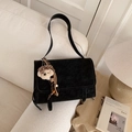 Close-up of black suede crossbody bag with cute plush puppy charm on a sofa - With Charm / Black