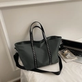 Dettaglio della borsa tote in nylon verde scuro con rivetti argentati sul manico nero - Grigio