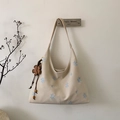 Dettaglio borsa hobo beige con ricamo a fiocco di neve blu e ciondolo a fiore - Con Ciondolo / Bianco