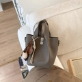 Détail du sac seau taupe en cuir avec fermoir rotatif en métal et breloques décoratives - Avec Pendentif / Gris