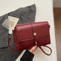 Borsa a tracolla in pelle opaca rosso scuro con fibbia in metallo, scena minimalista - Borgogna