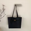 Detail van de zwarte tote bag met kiezellederen textuur en goudkleurige draaisluiting - Zwart