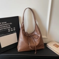 Dettaglio della borsa hobo marrone caramello con decorazione a fiocco e texture in pelle - Marrone