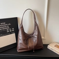 Detail of soft brown hobo bag featuring decorative bow and elegant leather grain texture - Coffee