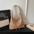 Detail view of khaki hobo bag with ribbon bow and embossed logo on minimalist background - Khaki