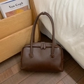 Close-up of dark brown glossy leather handbag with double handles and metal zippers - Brown