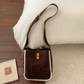 Detail einer dunkelbraunen Wildleder-Eimertasche mit weißem Kunstfellbesatz und Goldverschluss - Braun